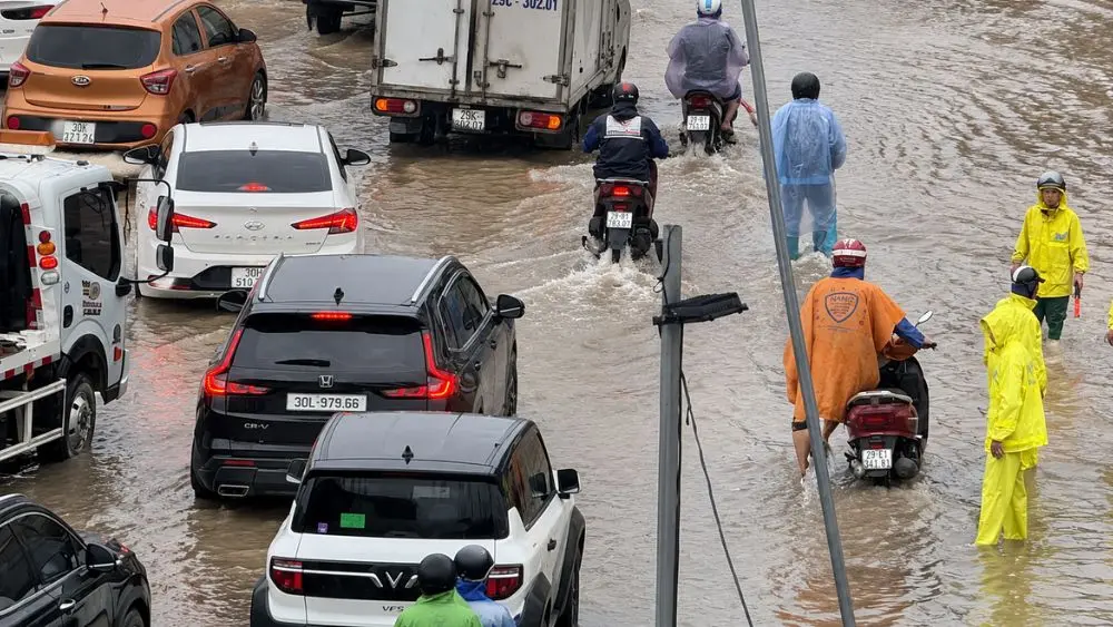 Mưa lớn gây ngập, ùn tắc tại nhiều tuyến đường Hà Nội. Công nhân thoát nước ứng trực, hướng dẫn phương tiện qua điểm ngập.